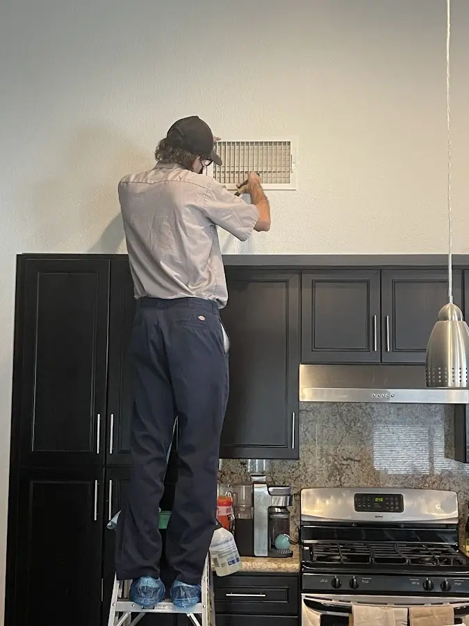 Technician inspecting an air vent during HVAC service in Baton Rouge